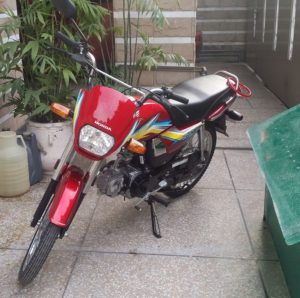 a small 70cc red honda motorcycle