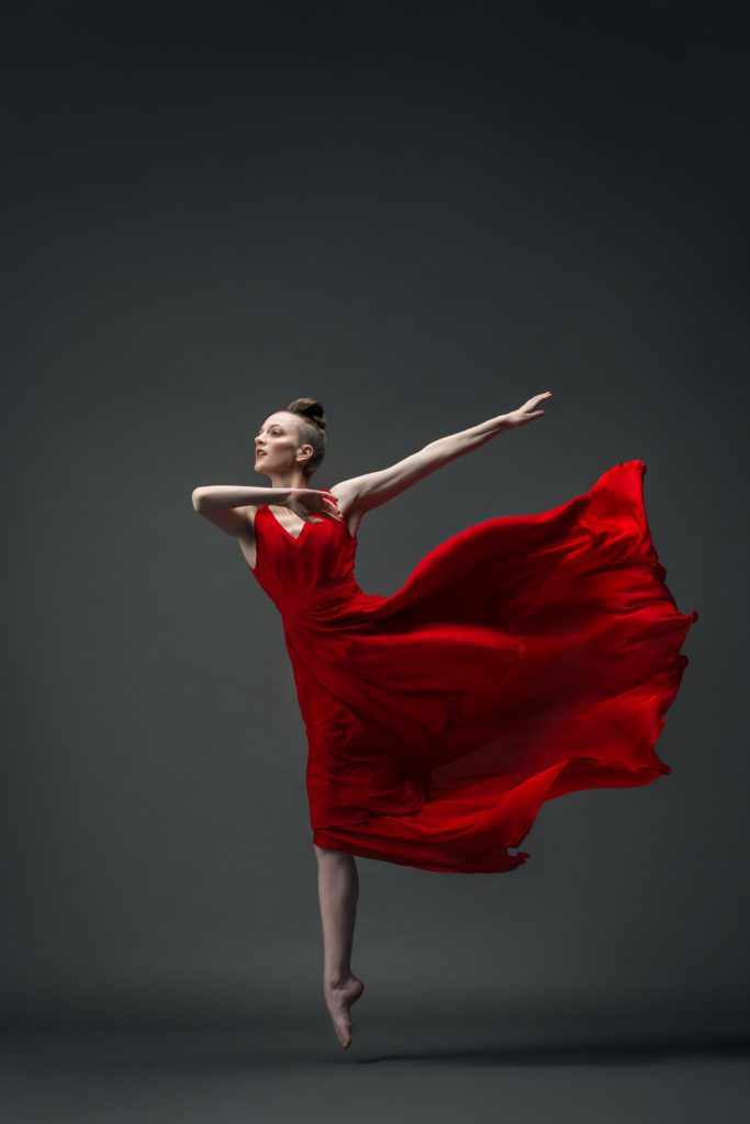 Gillian in a red dress leaping in an arabesque