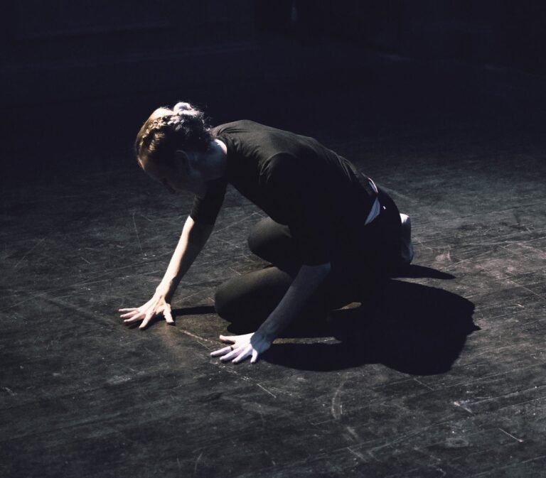 gillian kneeling on the ground with hands splayed against the stage