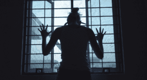 a person with both hands against a barred window