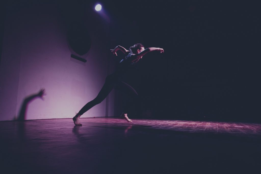 a side angle of a dancer running with dramatic lights