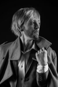 Gillian as a man in a suit with a jacket looking to the right