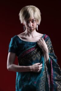 Gillian as a man in a sari looking into the camera