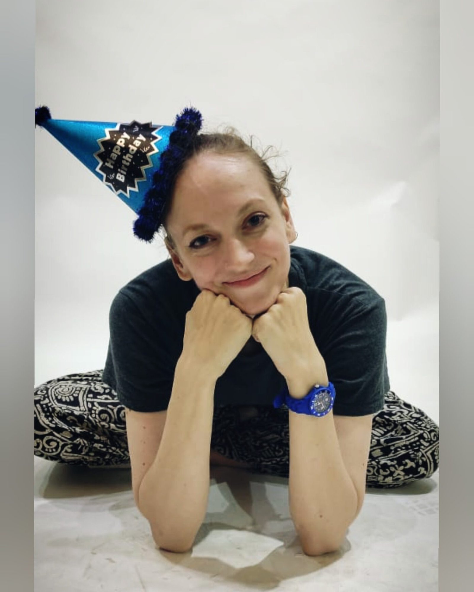 Gillian in a party hat with chin propped on hands smiling at the camera