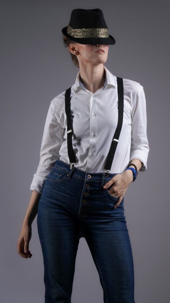 gillian wearing suspenders with a fedora half covering her face