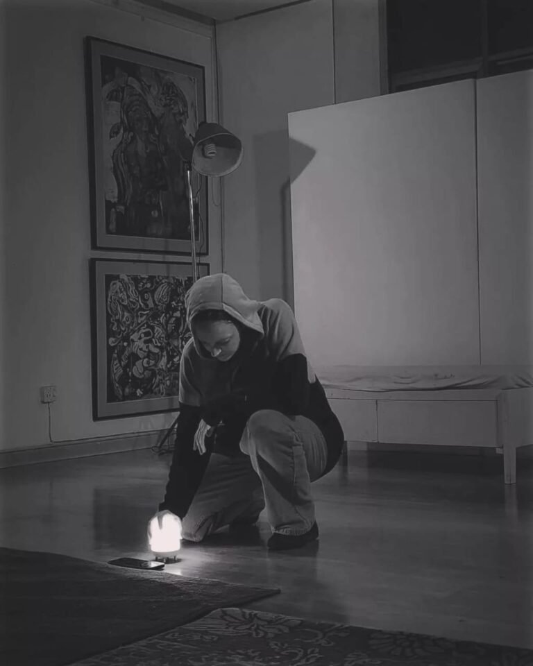 Gillian in a hoodie kneeling with a small lamp