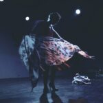 gillian performing in silhouette with a flowered scarf flowing in front of her