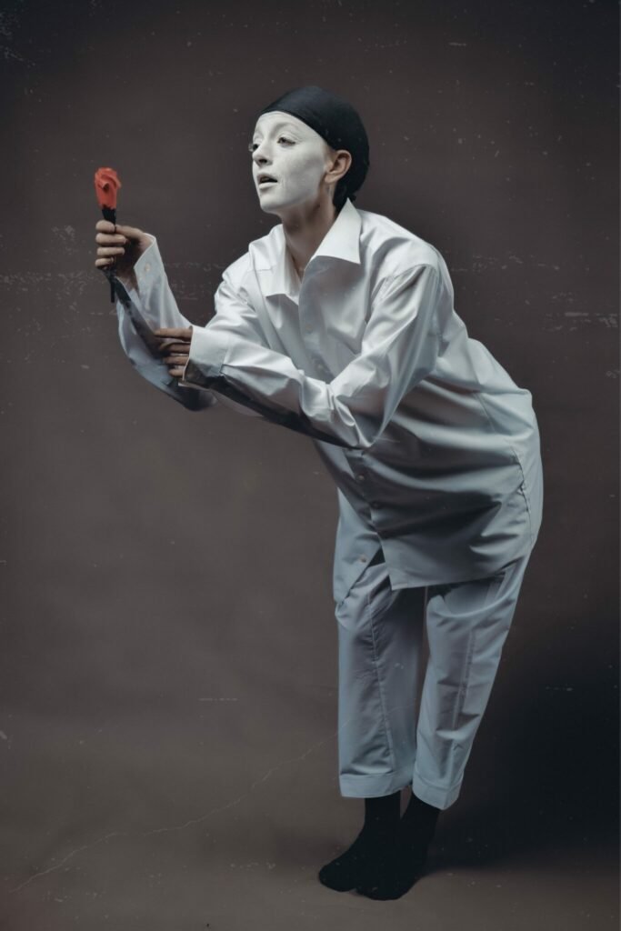 Gillian as pierrot holding out a flower