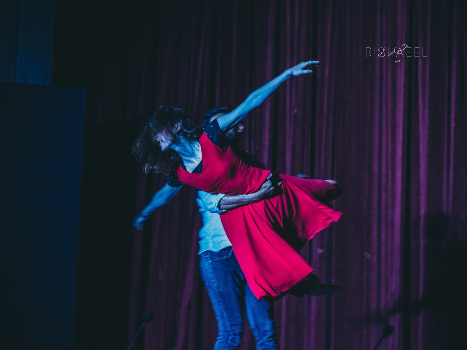 a man holding a woman in a red dress in a dance lift