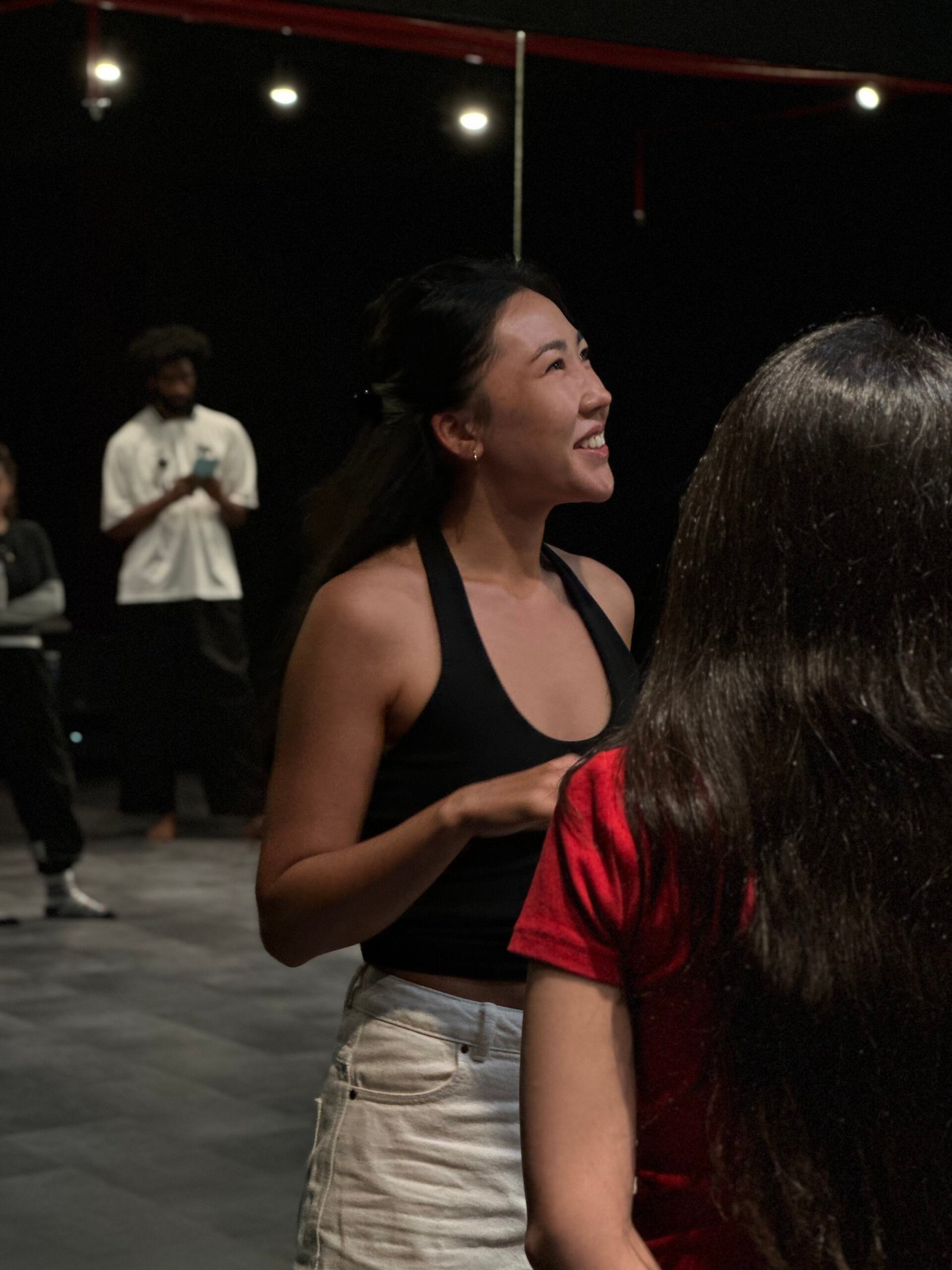 A person speaking to another with their back to the camera, looking to the right and smiling