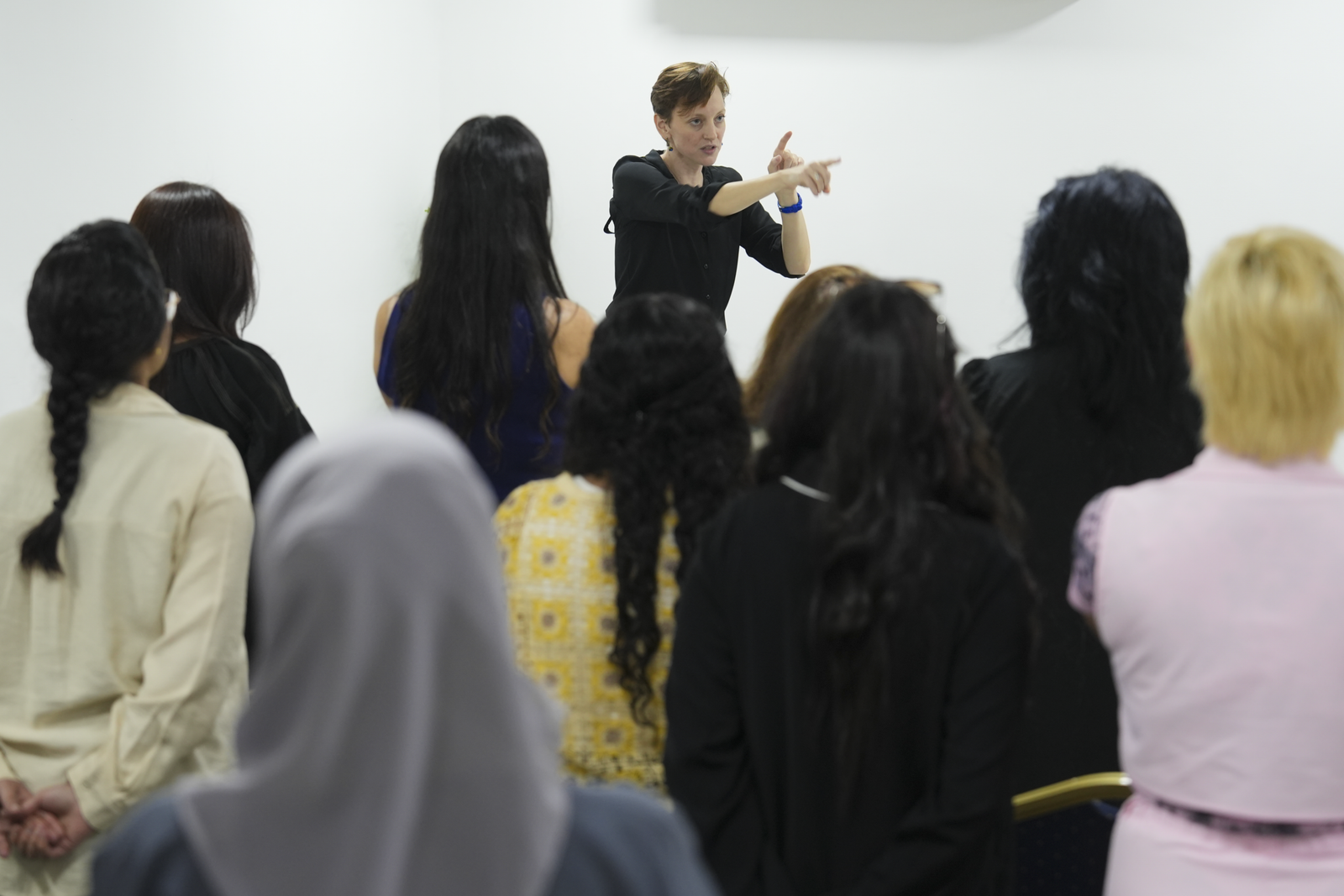 Gillian at the front of a large class, pointing and gesturing