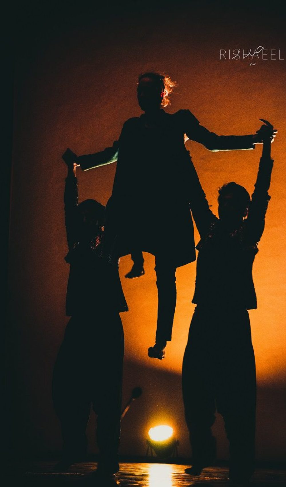 three silhouetted dancers, two dancers lifting the third above their heads by the arms